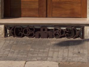 Tricase - via San Demetrio - Grata  in ferro battuto di una finestra di uno scantinato,  che ripropone gli elementi del vecchio stemma comunale: le tre case